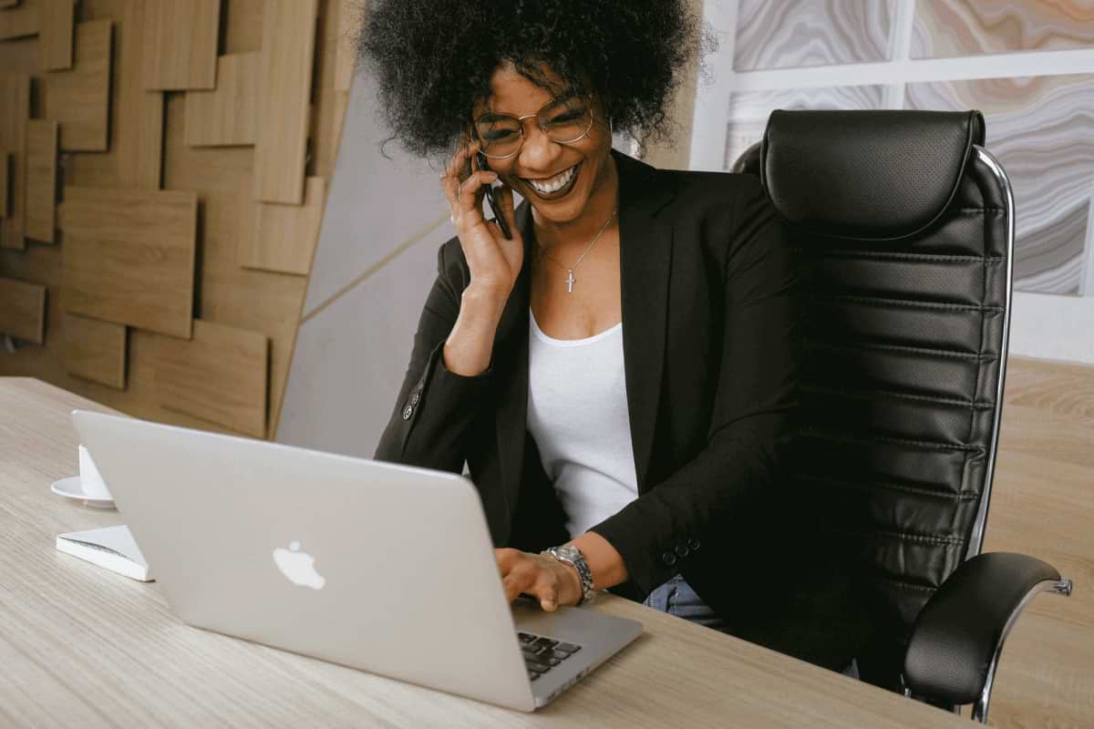 femme qui rigole au téléphone et devant son laptop