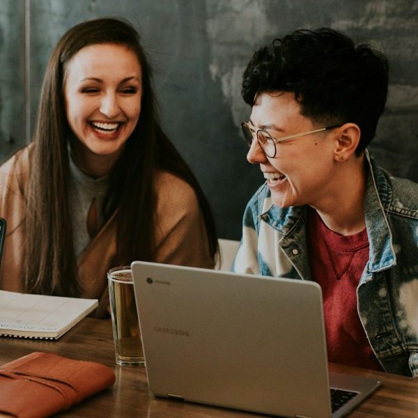 deux femmes rigolent ensemble devant un laptop